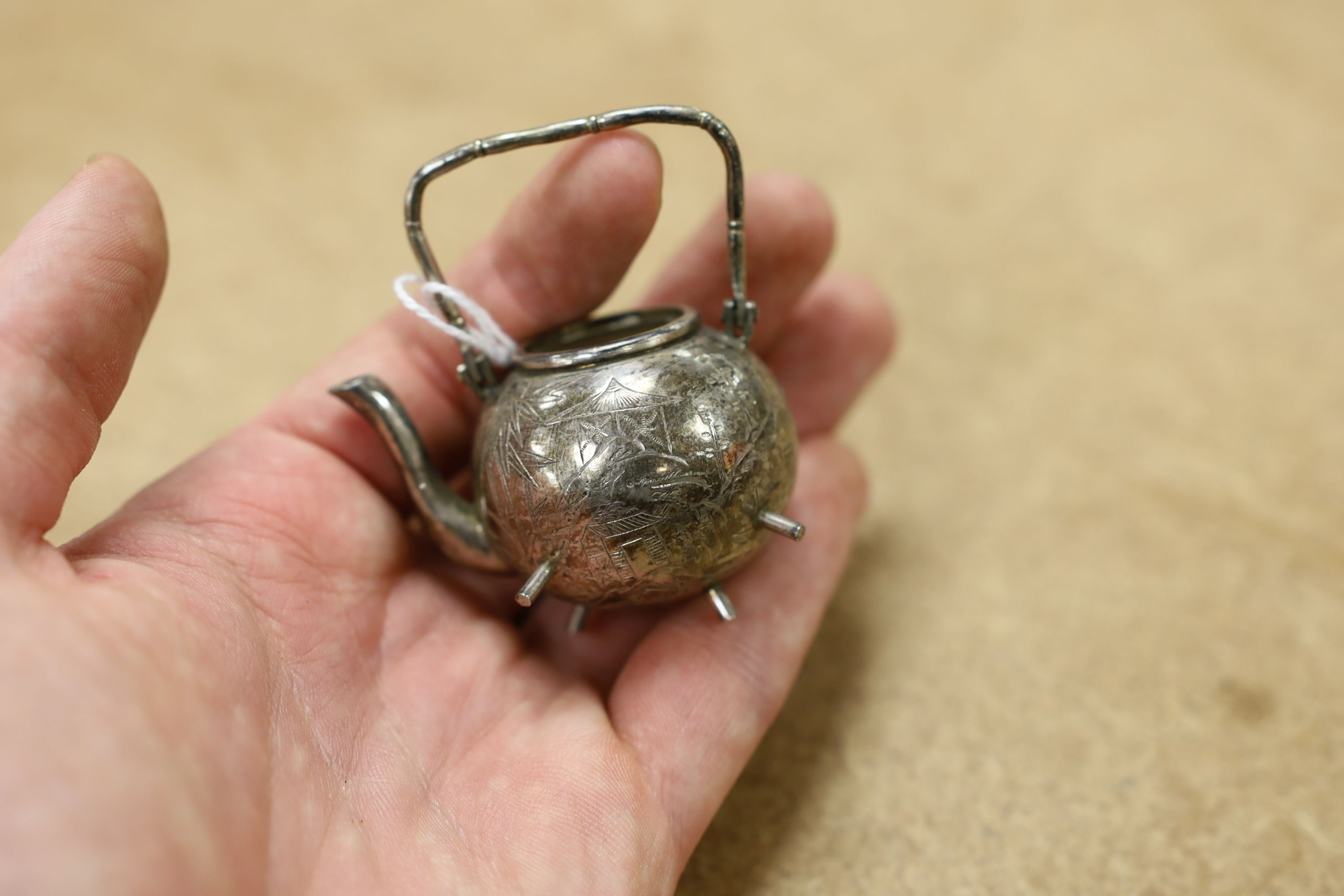 Six assorted miniature white metal items including a Chinese tea kettle on stand (lacking lid), height 93mm, maker CS, a similar rickshaw with driver, maker CH, a Chinese condiment and three other items.